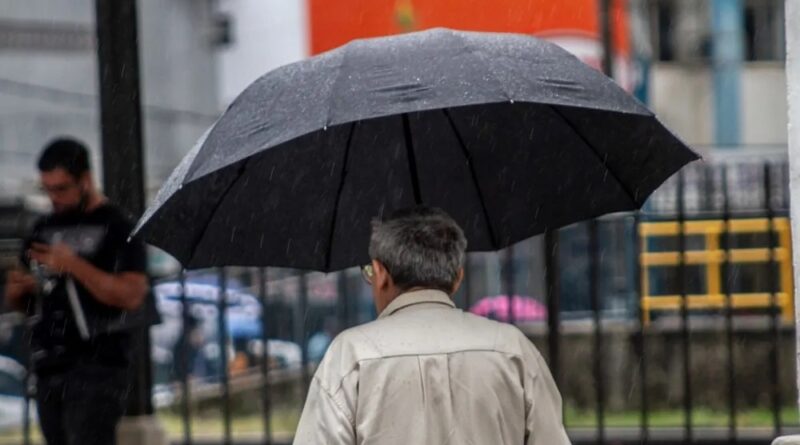 Homem segurando guarda-chuva na chuva